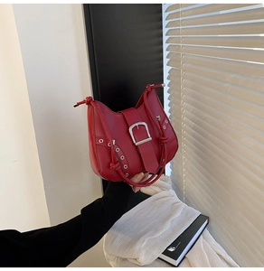Detail of red PU leather bag with large silver buckle and rivet studs on the side