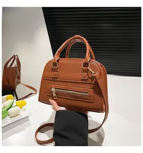 Close-up of brown lychee grain leather Boston bag with elegant gold zipper and metal hardware