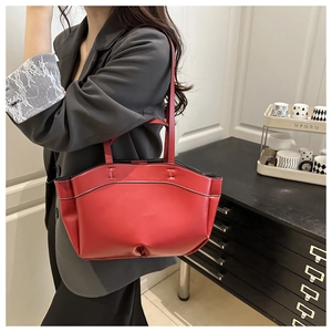 Detail of red leather tote bag showing white contrast stitching and slim shoulder straps