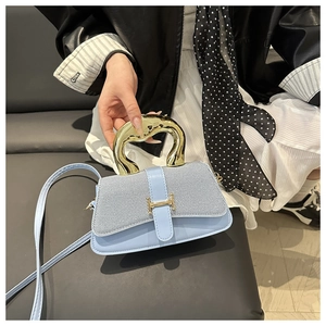 Close-up of light blue handbag with gold H-buckle and elegant metallic handle