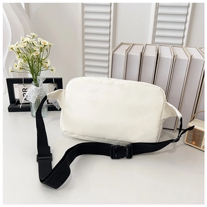 Detailed view of white nylon crossbody bag with black adjustable strap and buckle closure
