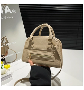 Detail of beige lychee pattern tote bag with functional zipper pocket and round handles