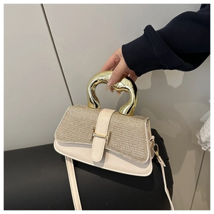 Close-up of the elegant H-shaped gold metal handle and clasp on a beige sequin handbag
