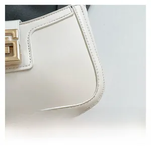 Detail of white glossy leather handbag with double stitching and golden buckle