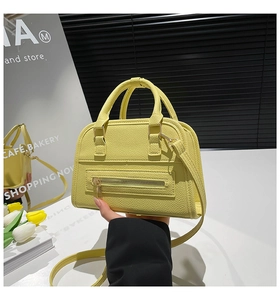 Detail of yellow boston bag featuring lychee texture leather and golden zipper hardware