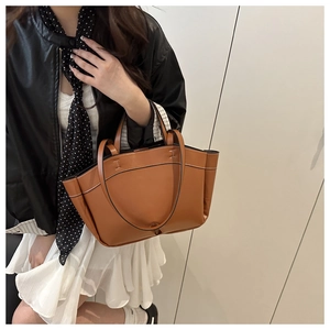 Brown leather tote bag featuring wing side design and stylish black polka dot scarf detail
