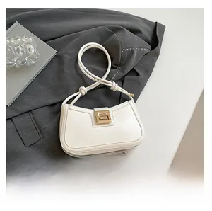Detail view of mini cream half-moon bag with gold buckle and knotted rope strap