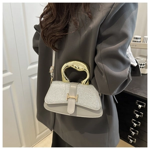 Detail of silver sequin crossbody bag with gold H-buckle and metallic curved handle