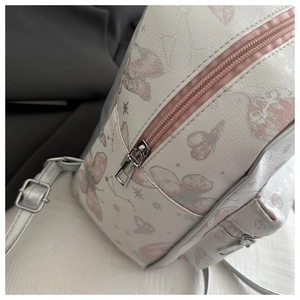 Detail of pink butterfly print and silver metal zipper on white college style backpack