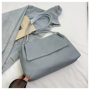 Detail of light blue denim texture tote bag with silver chain strap on white background