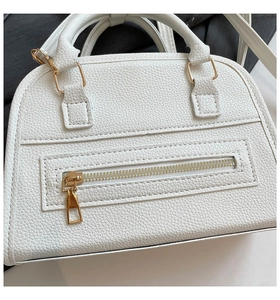 Close-up of white pebble leather Boston bag featuring gold zippers and stitching details
