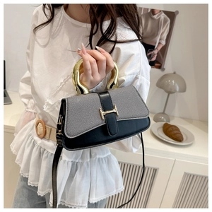 Detail of fashion crossbody bag featuring unique gold U-shaped handle and metal buckle closure