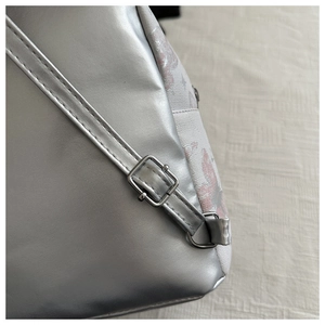 Detail of silver faux leather adjustable strap with metal buckle on floral fabric bag
