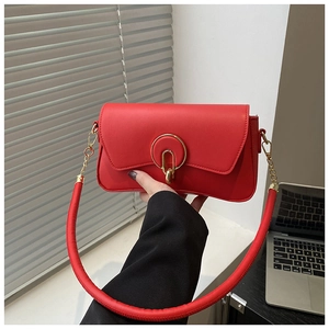 Detail of red leather crossbody bag featuring gold ring buckle and tubular shoulder strap