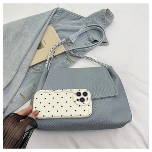 Close-up of light blue woven texture bag showing its capacity compared to a phone