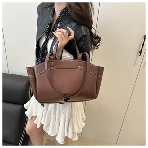 Detailed view of caramel brown tote bag with white contrast stitching and leather texture