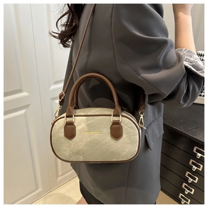 Detail of a retro color-block handbag with brown leather handles and gold fashion text