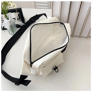 Close-up of the spacious main compartment and drawstring front pocket on a white crossbody bag