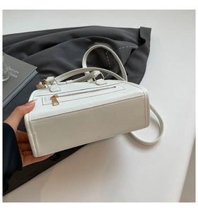 Detail shot of white pebbled leather boston bag with premium gold zipper and hardware