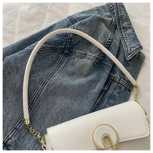 Gros plan d'un sac à main blanc avec boucle ovale dorée et détails de chaîne métal
