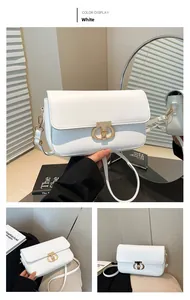 Detail view of white crossbody bag with elegant golden oval clasp and adjustable strap