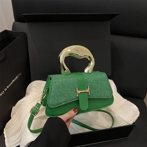 Chic green sequin crossbody bag with gold metal handle on elegant display