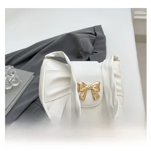 Detail showing white pleated shoulder bag with gold metal bow and smooth PU leather texture
