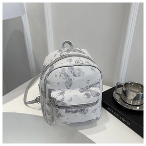 Macro shot of silver butterfly prints on cream PU leather mini backpack detail