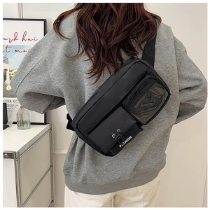 Detail of black nylon crossbody bag with transparent PVC pocket and FASHION tag worn by model