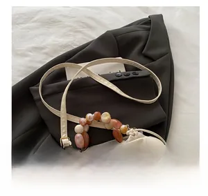 Détail de la poignée en perles ambrées et du cuir synthétique du sac seau beige