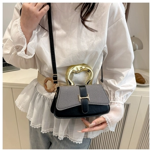 Detail view of the gray and black panelled handbag with a gold metal handle and H-clasp