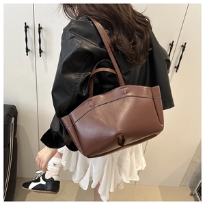 Detail of dark brown tote bag showing contrast stitching and premium leather texture