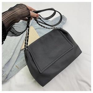 Close-up of black woven chain bag texture with metallic strap and minimalist style