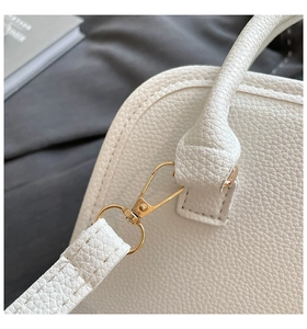 Detailed macro view of white pebble leather texture and gold metal hardware on bag