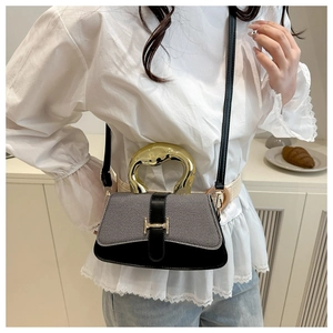 Detail of grey textured handbag with gold H-buckle and unique metal handle worn by model