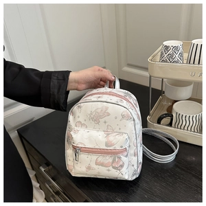 Close-up of butterfly and star prints on creamy white faux leather mini backpack