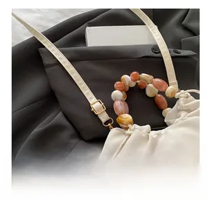 Detail of beaded handle and adjustable metal buckle on off-white canvas crossbody bag
