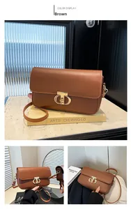 Detail of a brown leather crossbody bag featuring a semicircular gold buckle and adjustable strap