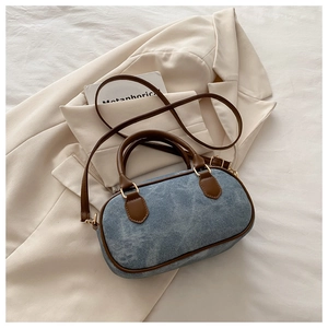 Detail of denim crossbody bag with brown leather handle on a stylish beige blazer