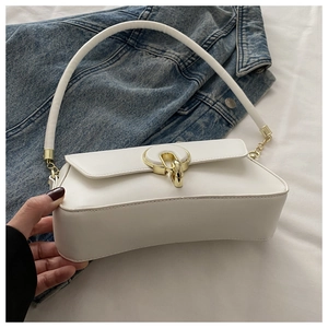Détail du sac à bandoulière blanc avec boucle fer à cheval dorée et chaîne sur denim