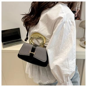 Detail of fashion crossbody bag with unique gold metal handle and woven texture flap
