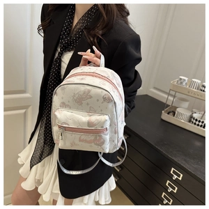 Close-up of a mini white PU leather backpack with pink butterfly prints and silver zippers