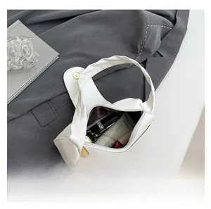 Top view of open white pleated shoulder bag showing spacious interior with cosmetic items