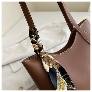 Gros plan du sac cabas en cuir marron avec un élégant foulard en soie au manche