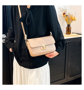 Close-up of beige leather crossbody bag with gold T-shaped metal buckle on a model