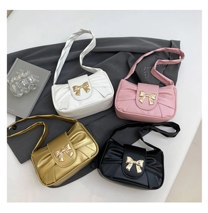 Detail view of four shoulder bags in white, pink, gold, and black with metal bows