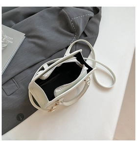 Detail view of white pebbled leather Boston bag interior with zipper divider and golden hardware