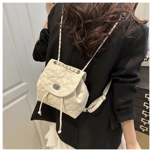 Detail of cream quilted mini backpack with heart stitching and silver chain strap