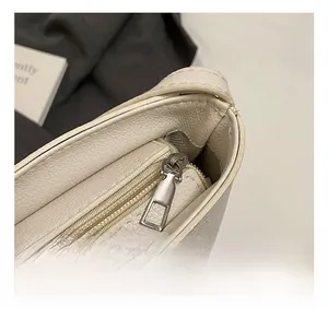 Macro detail of high-quality silver metal zipper on off-white lychee pattern bucket bag