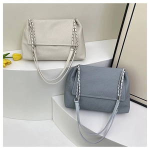 Detail of minimalist shoulder bags in cream and grey blue with metal chain straps
